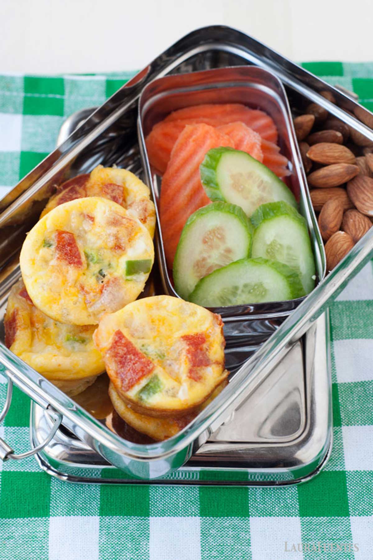 una lonchera con muffins de huevo, zanahoria, pepino y almendras