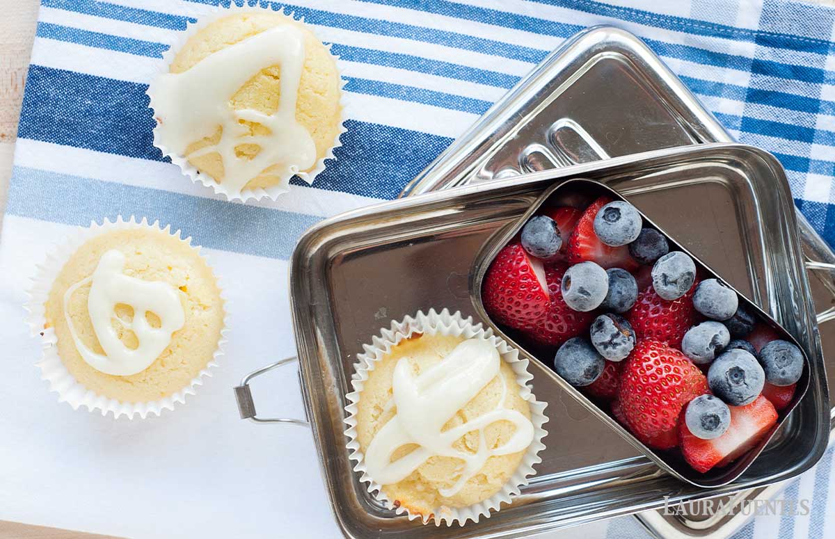 una lonchera con frutos rojos y tres muffins de limón