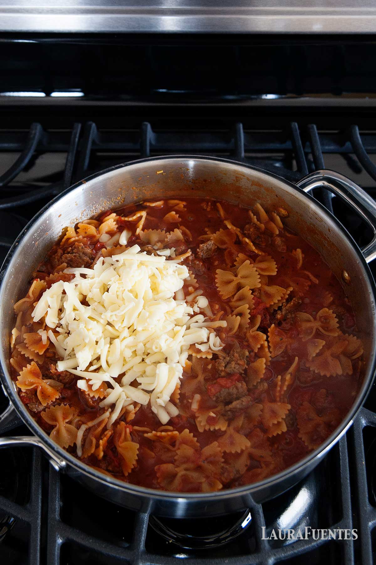 una sartén con pasta, carne picada, tomate y queso