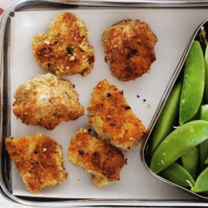 una lonchera con seis nuggets de pollo y un contenedor más pequeño con judías verdes