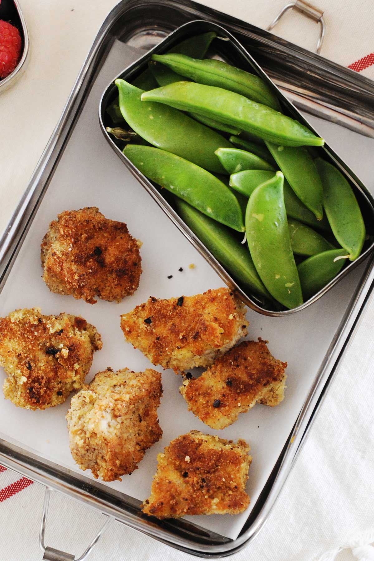 una lonchera con seis nuggets de pollo y un contenedor más pequeño con judías verdes