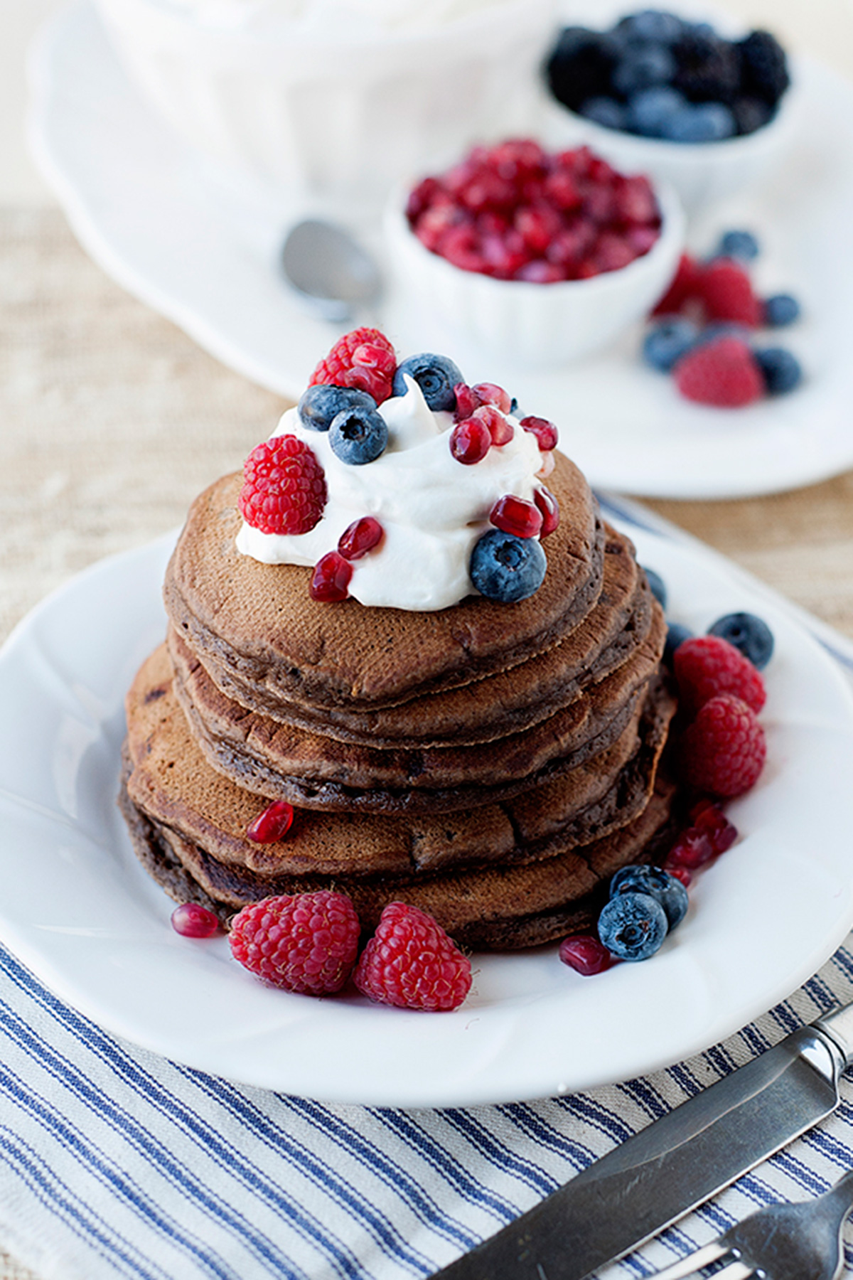 una pila de tortitas de chocolate con crema y frutos rojos encima