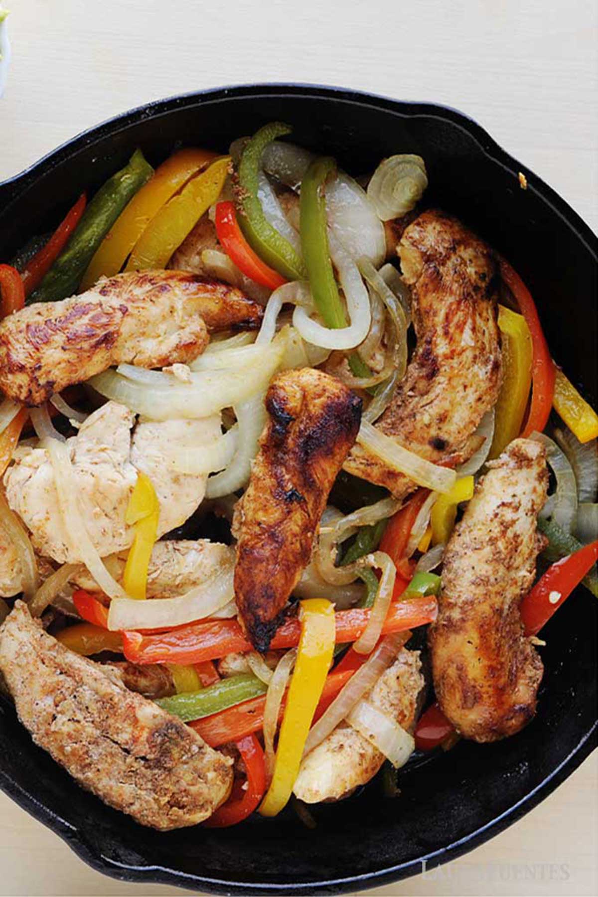 pollo con pimientos y cebolla en una sartén