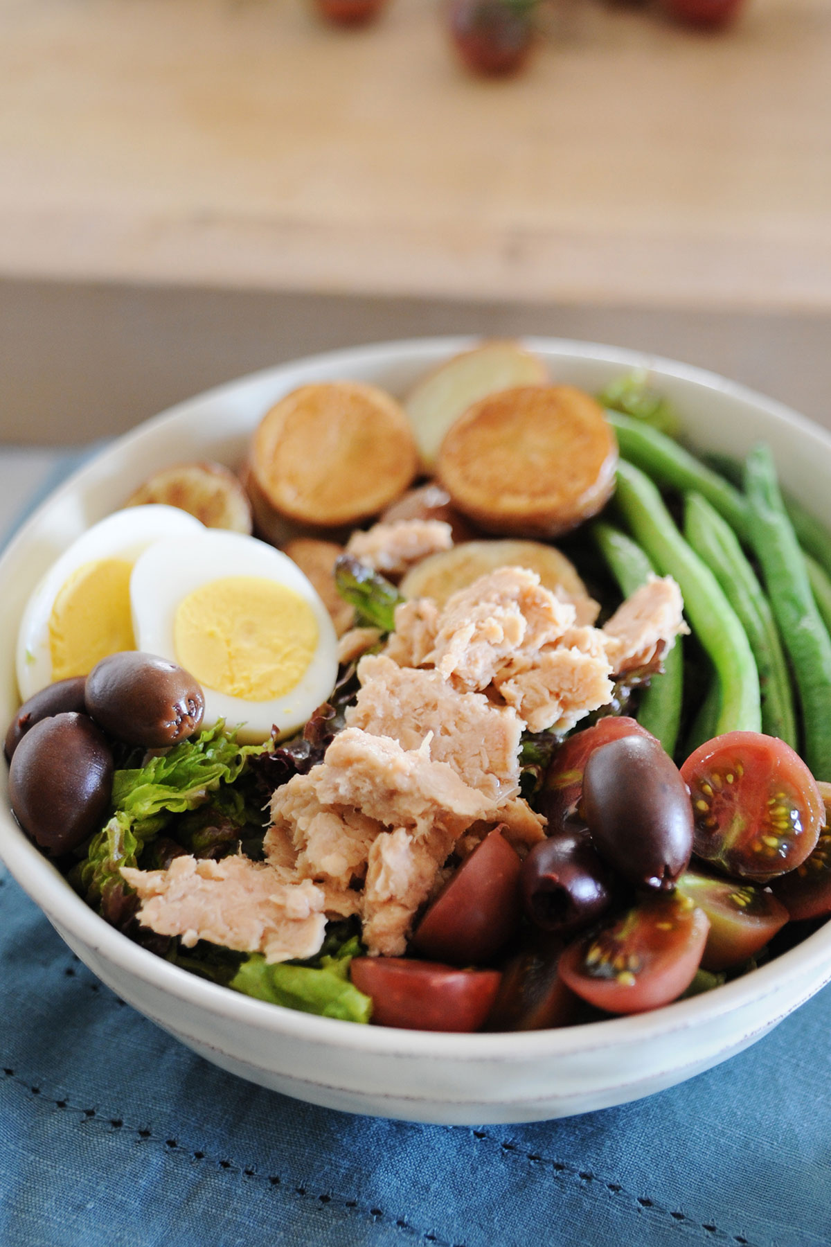 ensalada francesa con tomates, aceitunas, judias verdes, salmón, y lechuga en un bol
