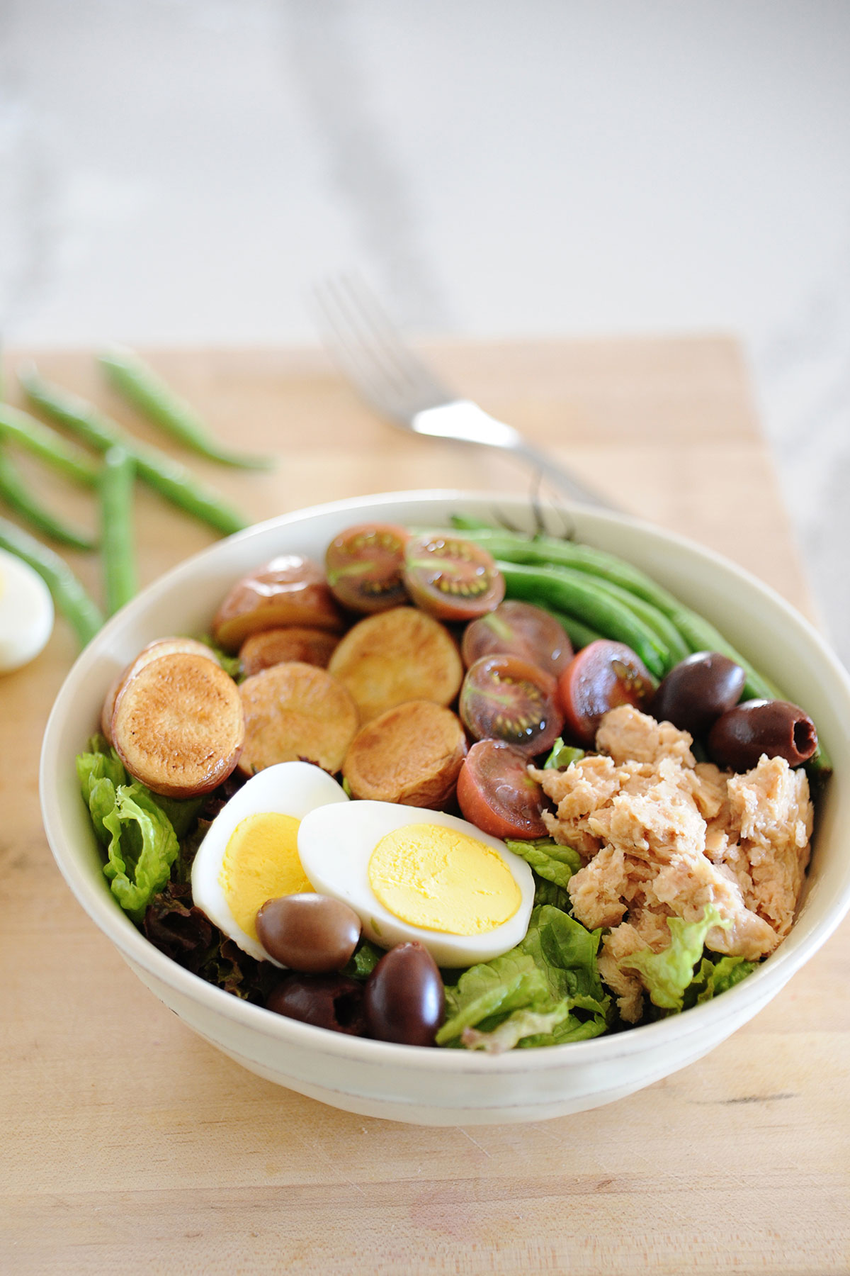 ensalada francesa con tomates, aceitunas, judias verdes, salmón, y lechuga en un bol