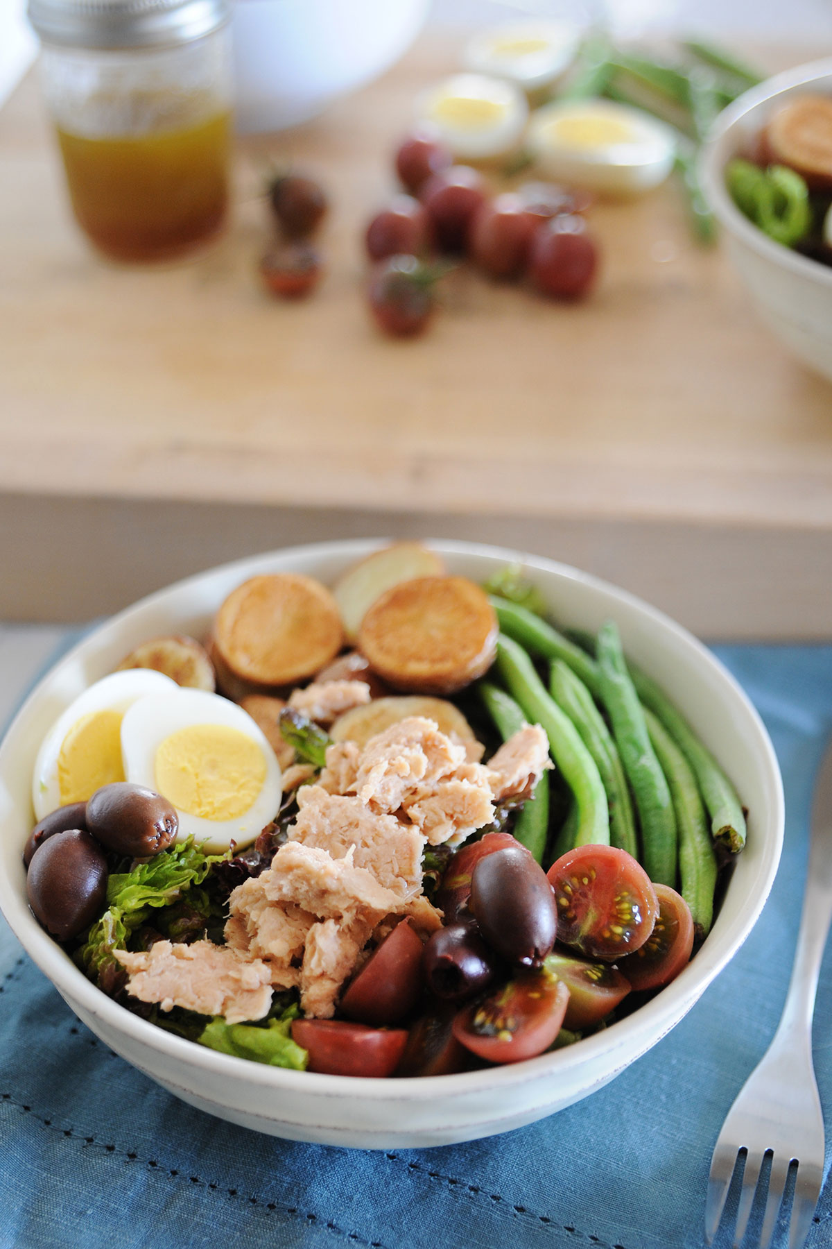 ensalada nicoise con tomates, aceitunas, judias verdes, salmón, y lechuga en un bol