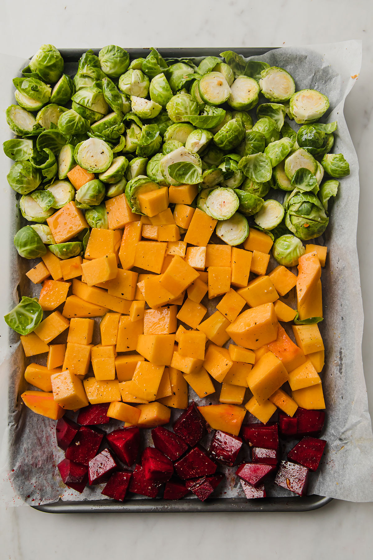 verduras cortadas para ser horneadas en una bandeja forrada con papel de hornear