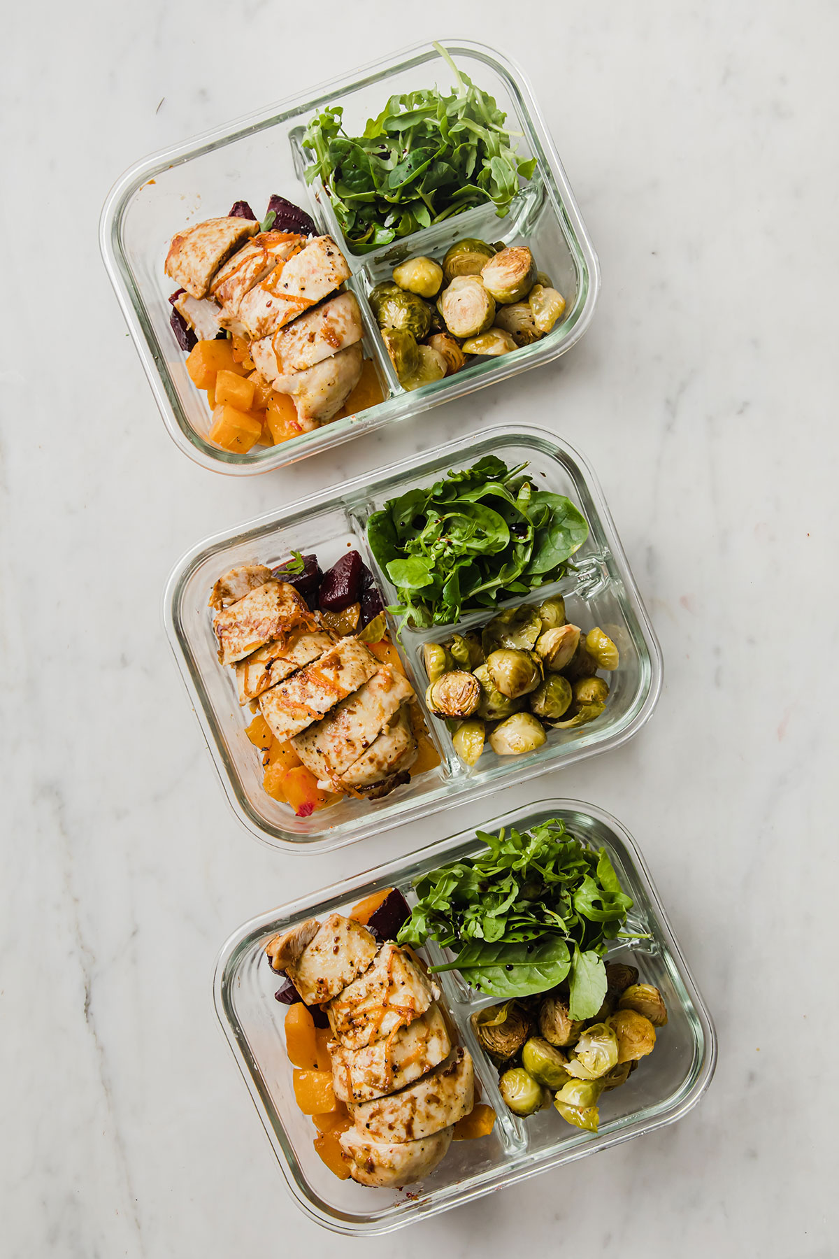 verduras horneadas, ensalada, y pollo horneado en tres cuencos para hacer meal prep