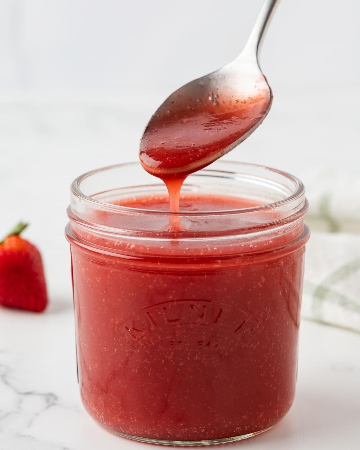unna frasco con sirope de fresa y una cuchara tomando un poco