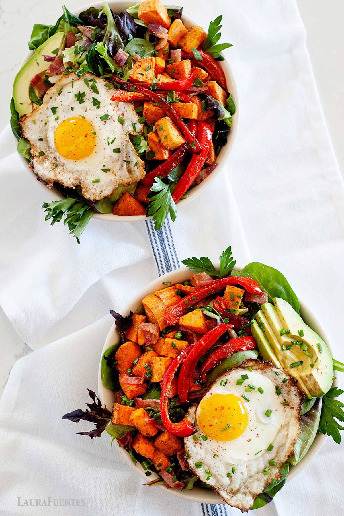 ensalada para cenar en dos boles con huevo frito, aguacate, pimientos y batata