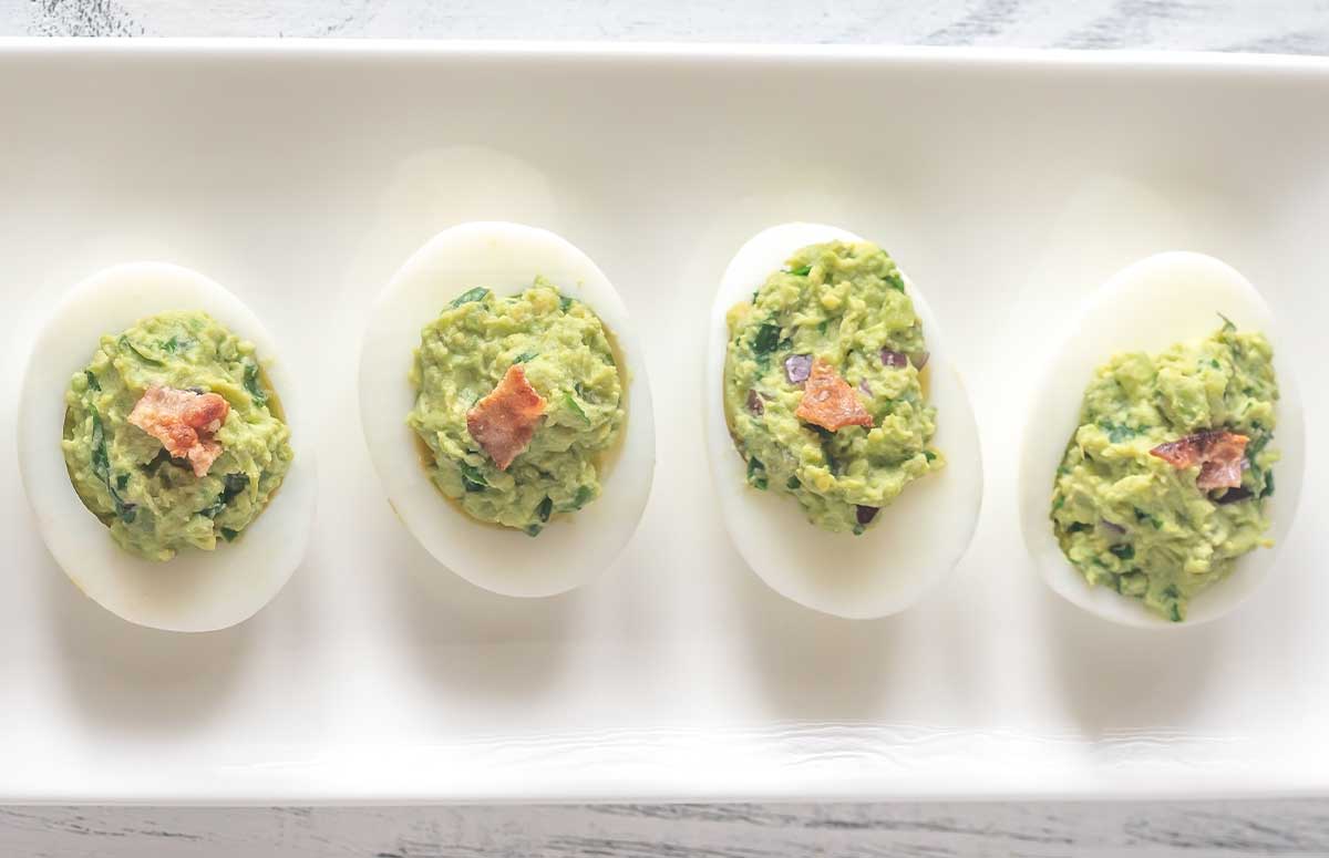 una bandeja con huevos rellenos de aguacate y atun