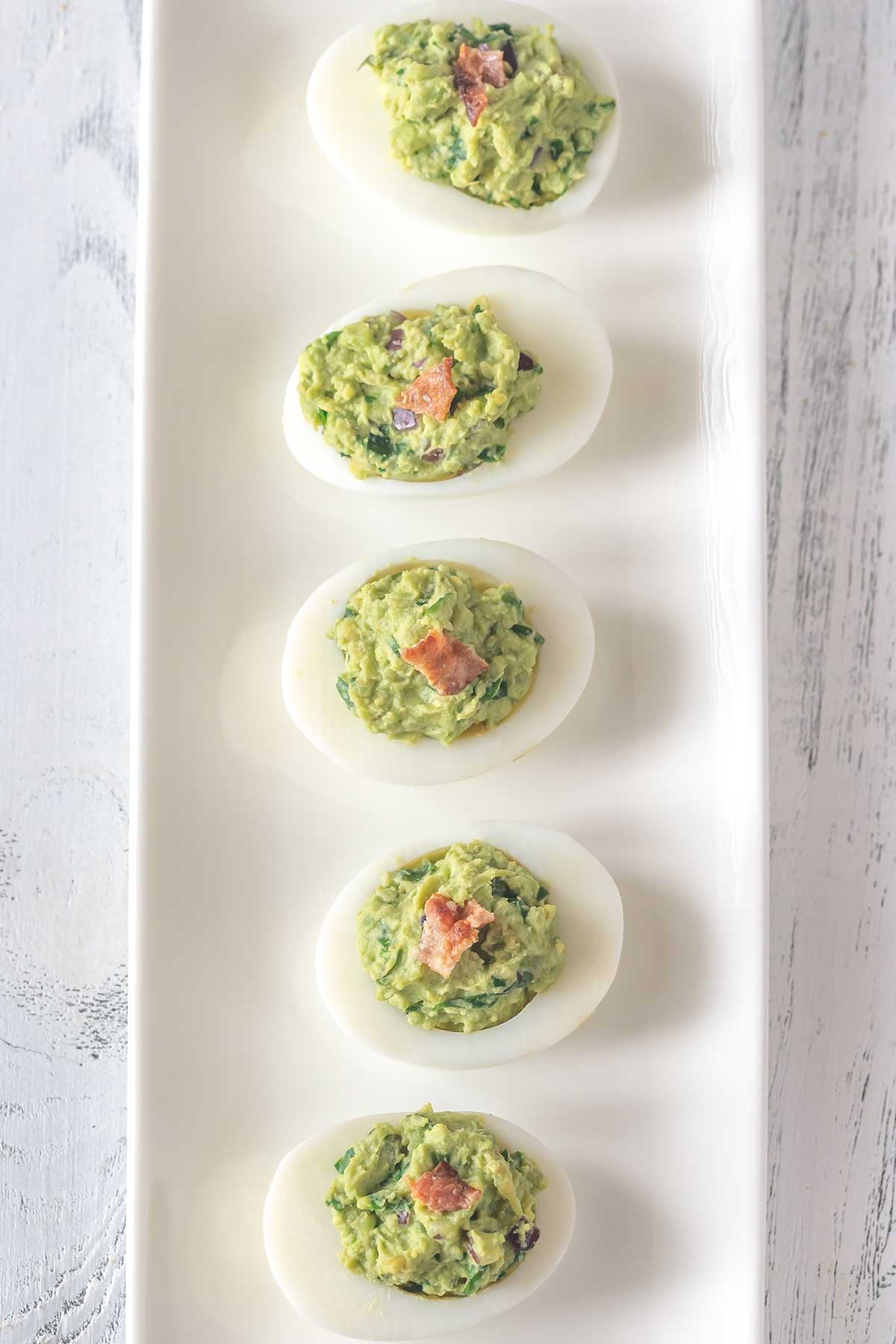 una bandeja con huevos rellenos de aguacate y atun