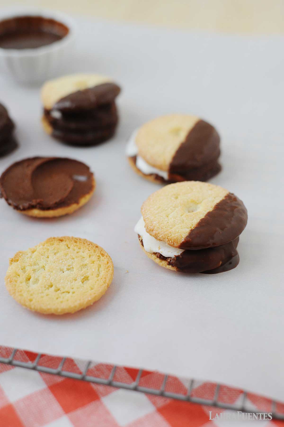 galletas con helado por encima con covertura de chocolate siendo armadas para hacer sandwiches de helado