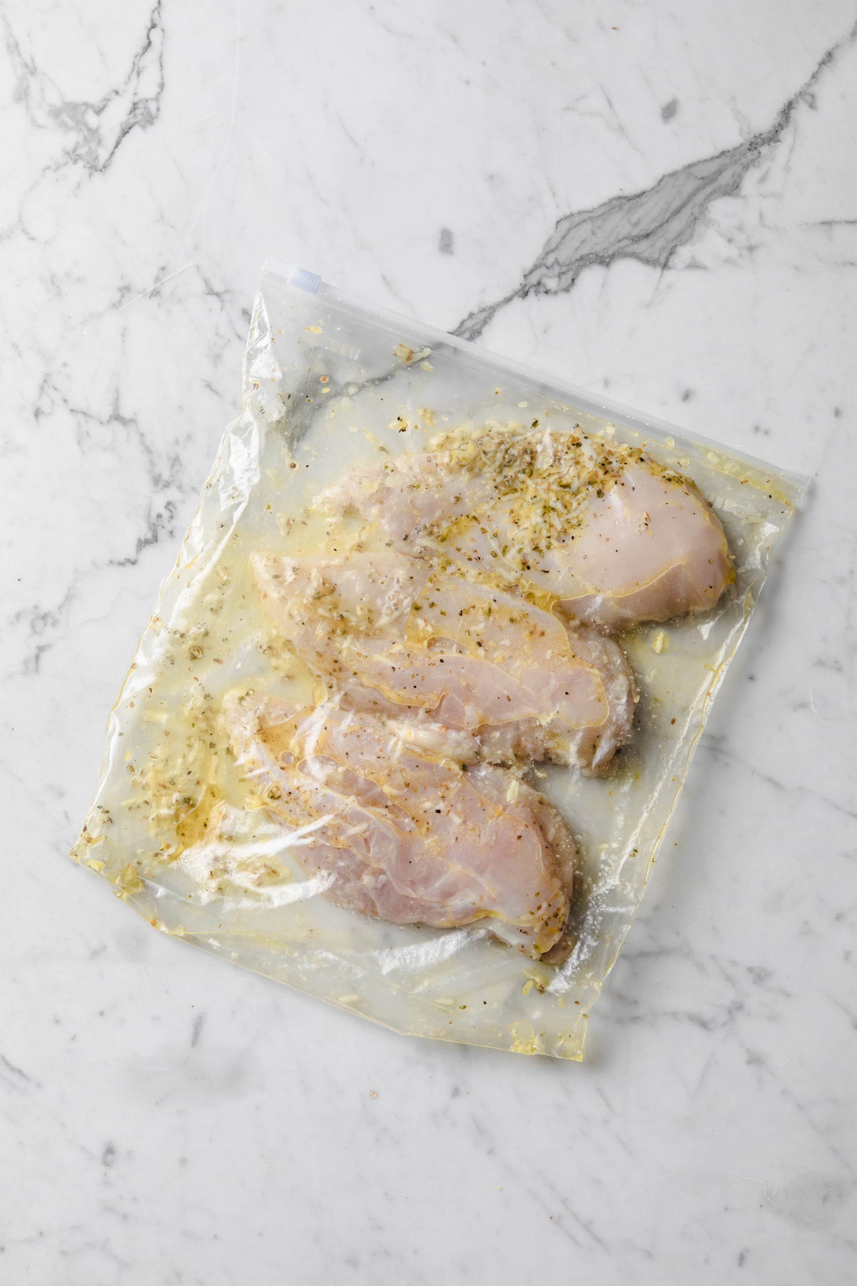 pechugas de pollo dentro de una bolsa zip con marinada de limón y hierbas