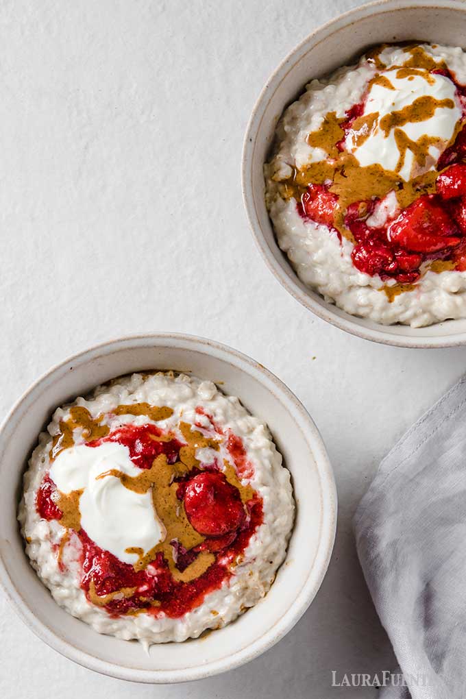 dos tazones de avena con proteina, fresas, mantequilla de almendras y yogurt griego.
