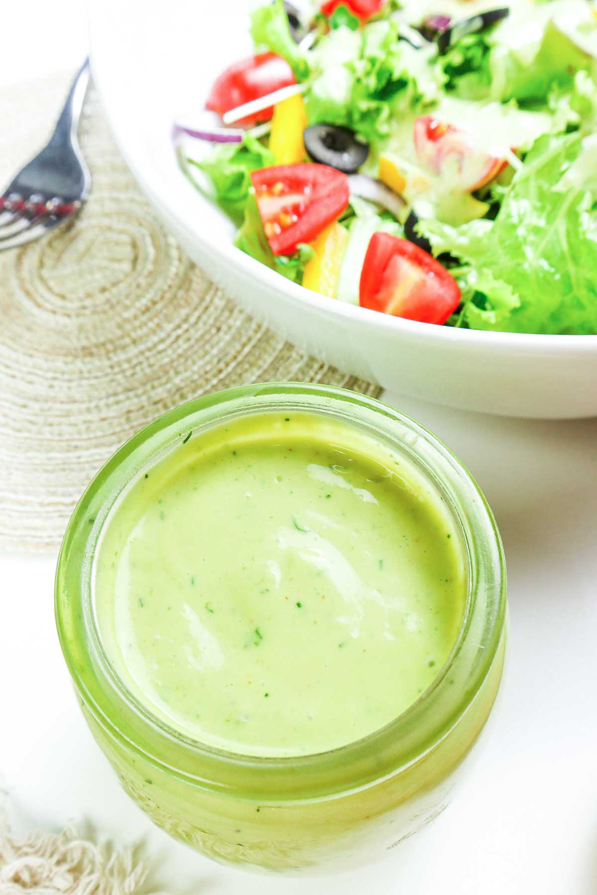 un tarro con Aderezo de Aguacate junto a un bol de ensalada