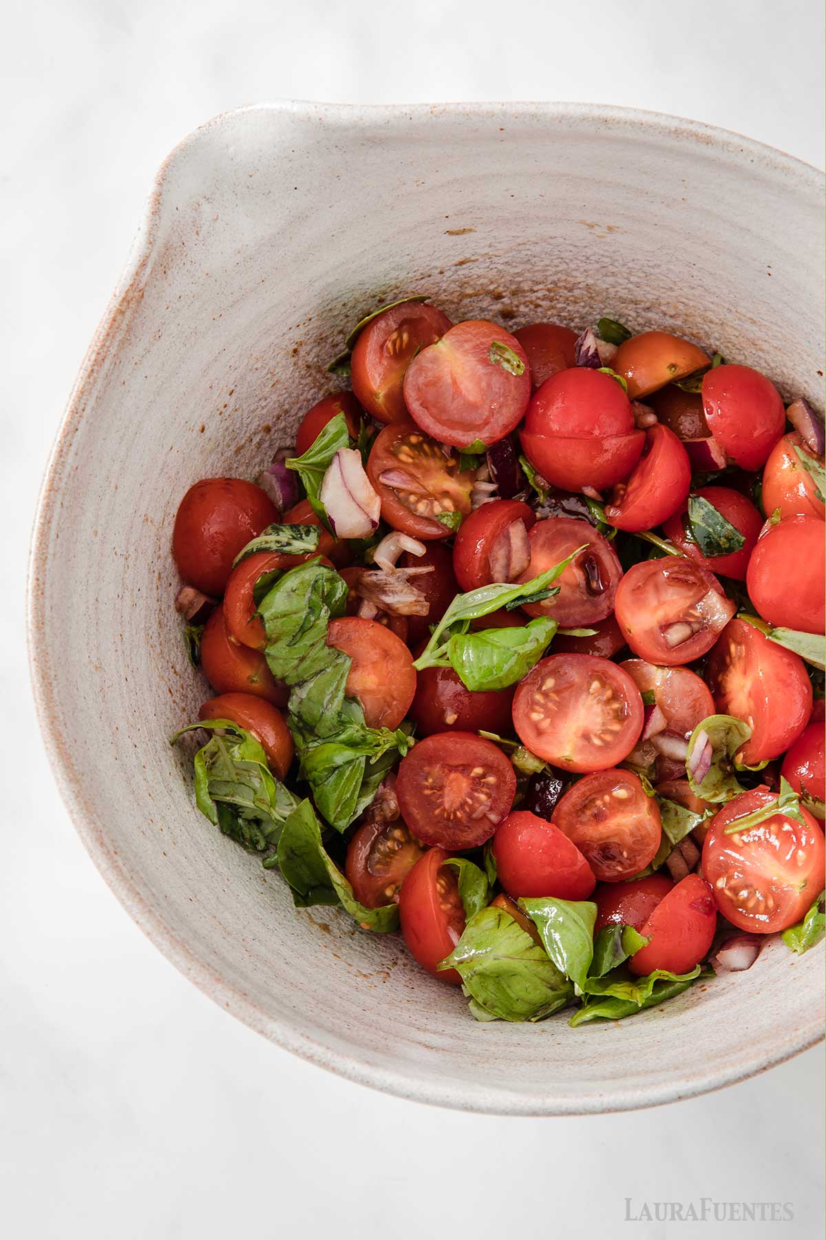 Un bol de ensalada de tomate, cebolla y albahaca