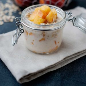 un frasco de avena nocturna con leche y melocotón