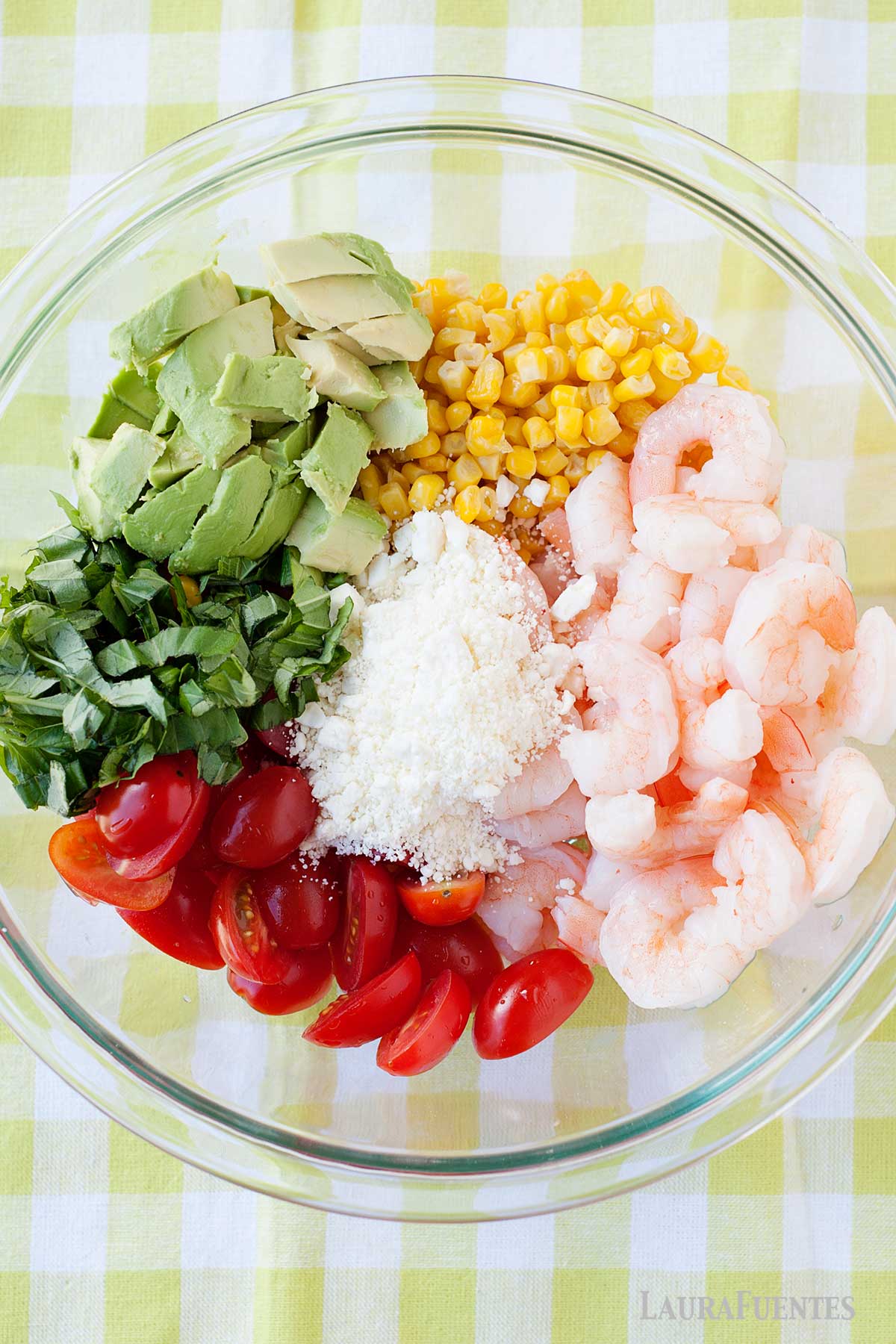 un bol con maiz, gambas, tomates, aguacate, albahaca y queso