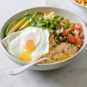 un bowl con avena cocida, huevo frito, aguacate, pico de gallo y cilantro