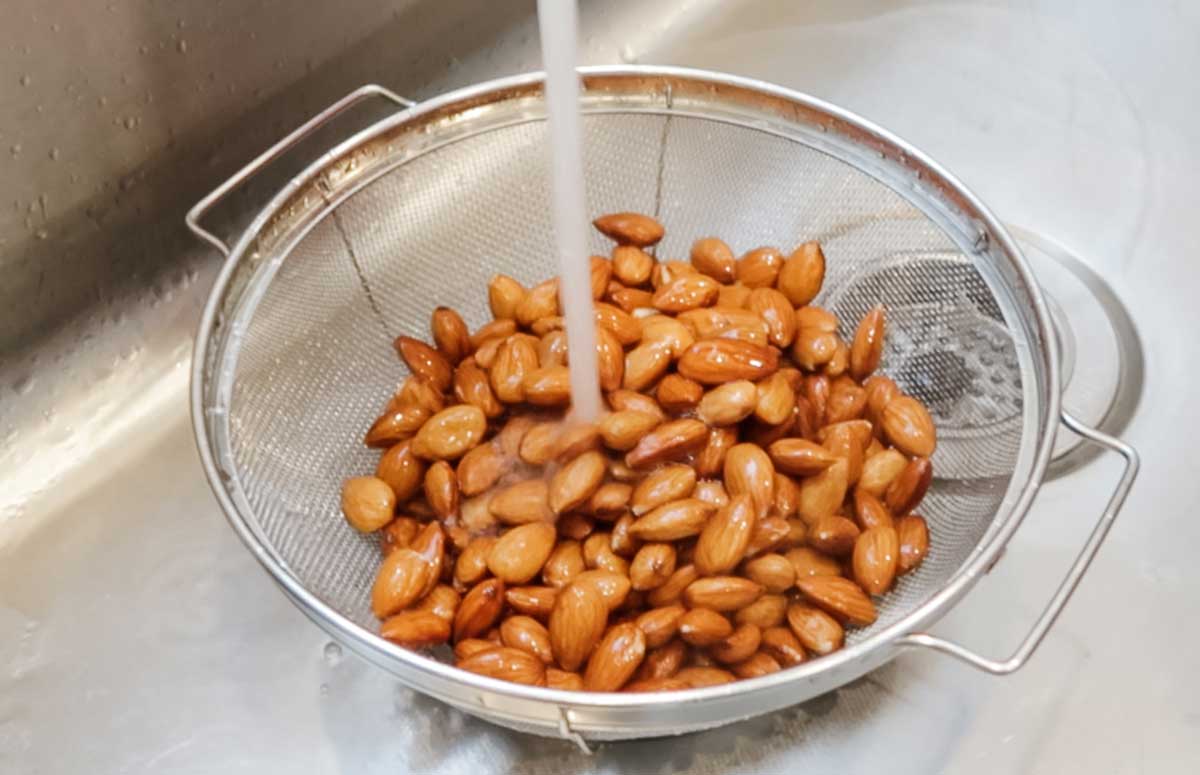 almendras crudas en un colador, debajo del grifo de agua