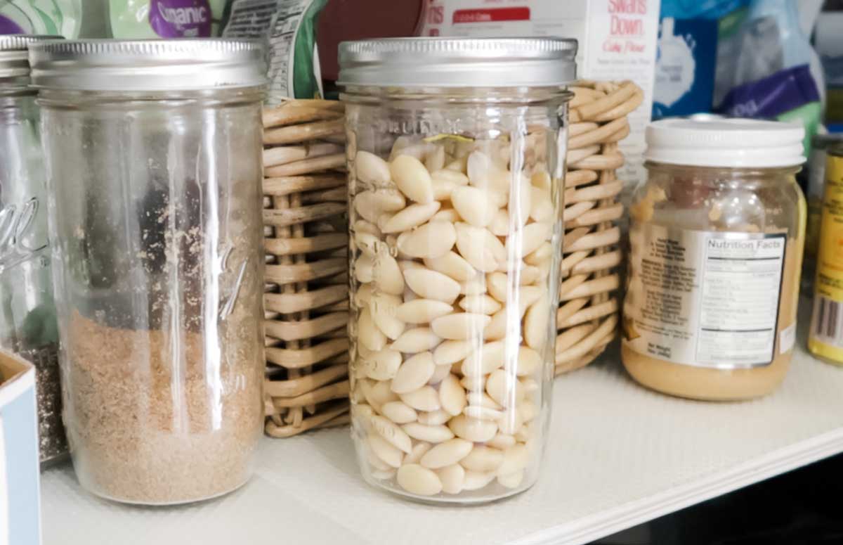 un frasco con almendras sin piel junto a otros frascos en una alacena