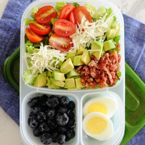 lonchera con ensalada BLT, huevos duros y arándanos