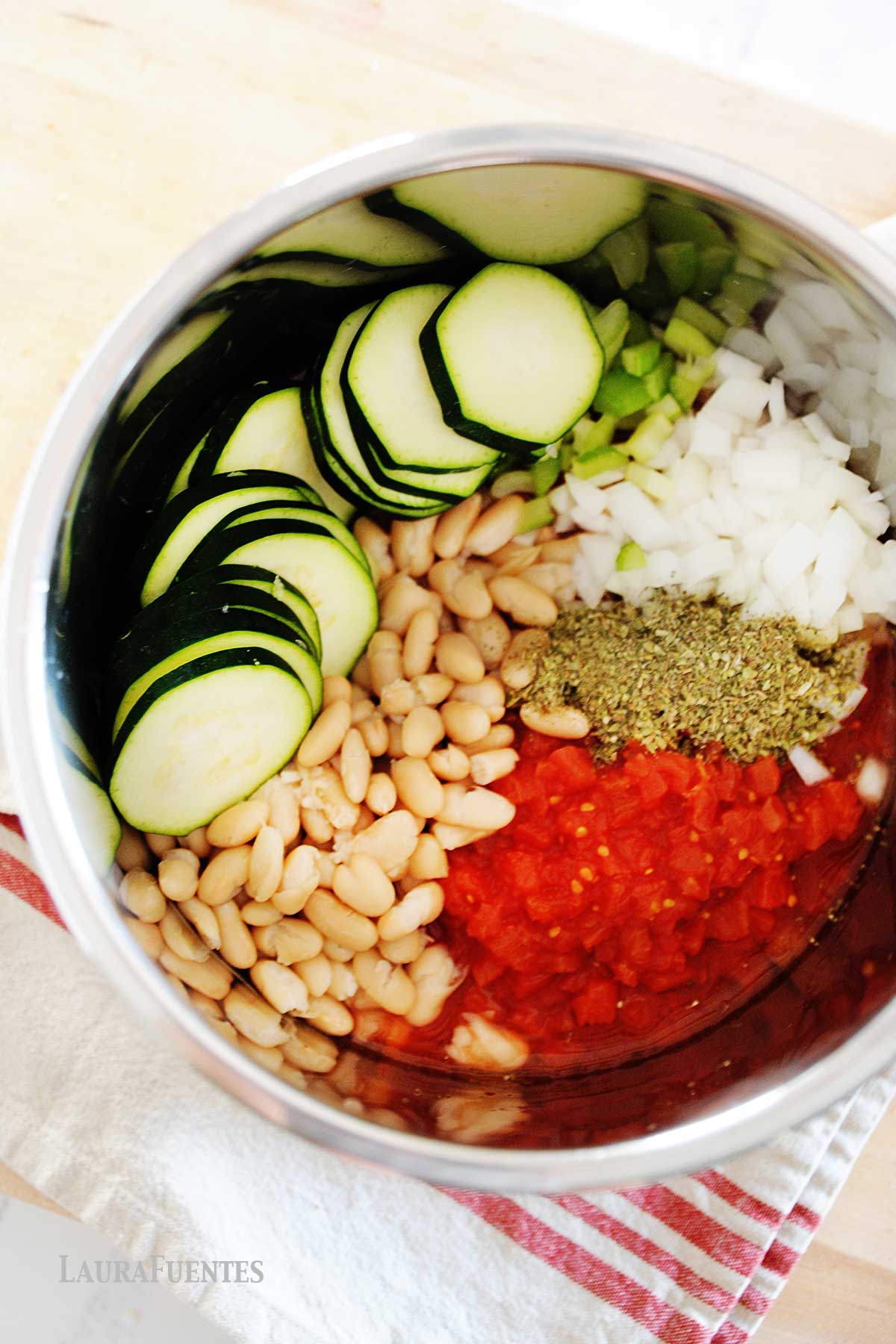 un recipiente con alubias, calabacín, tomate triturado, cebolla, apio y especias