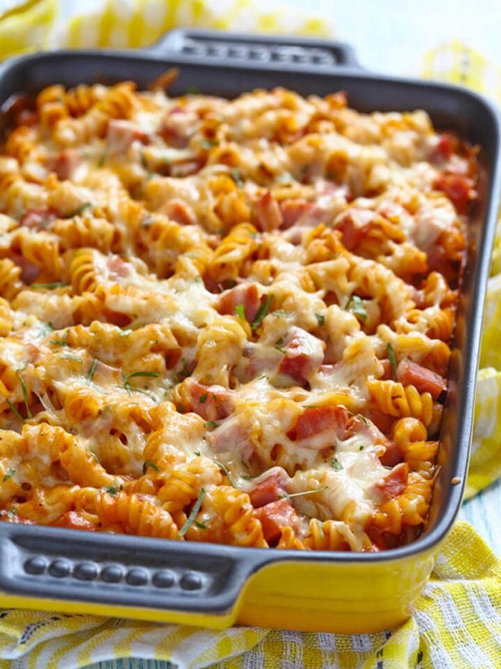 una fuente de pasta al horno gratinada con albahaca, jamón y queso