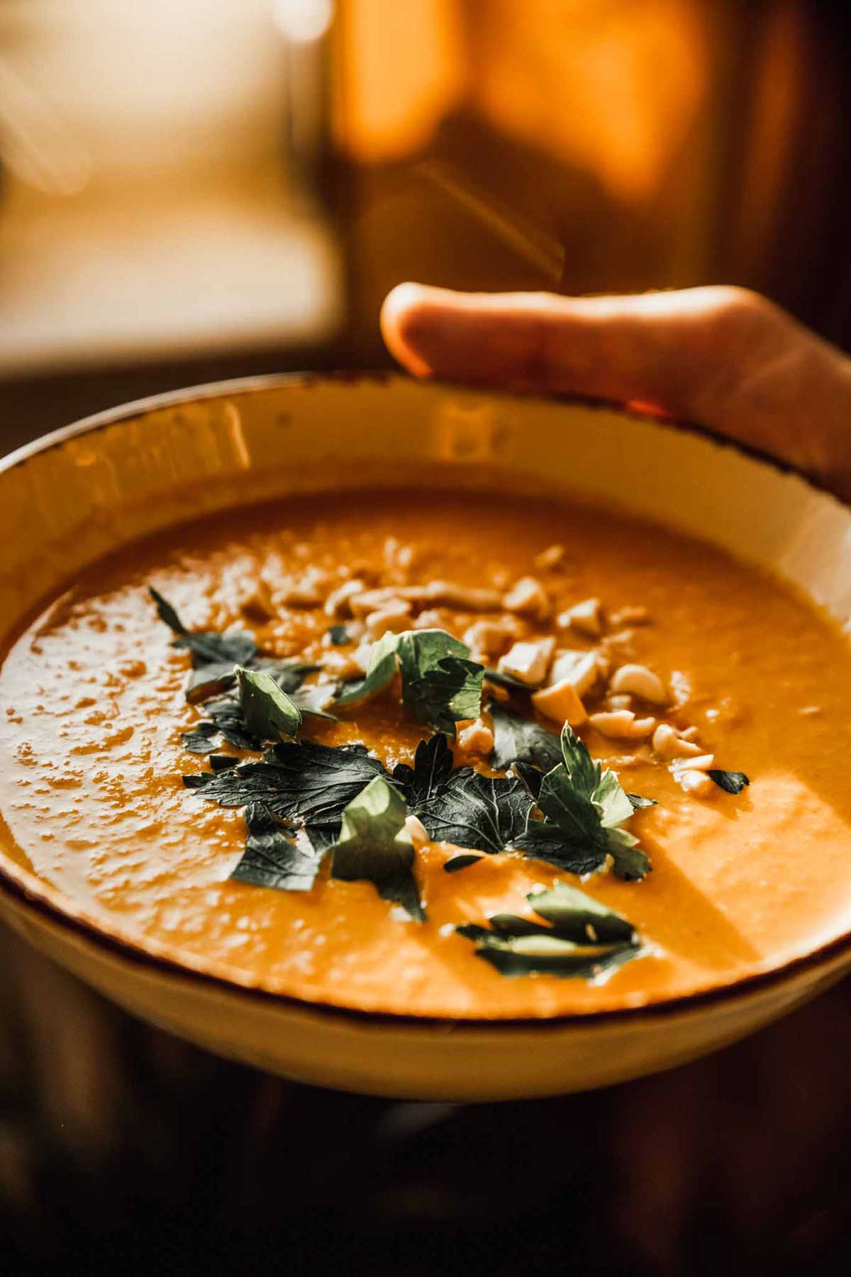una persona sosteniendo un tazón de sopa crema de calabaza