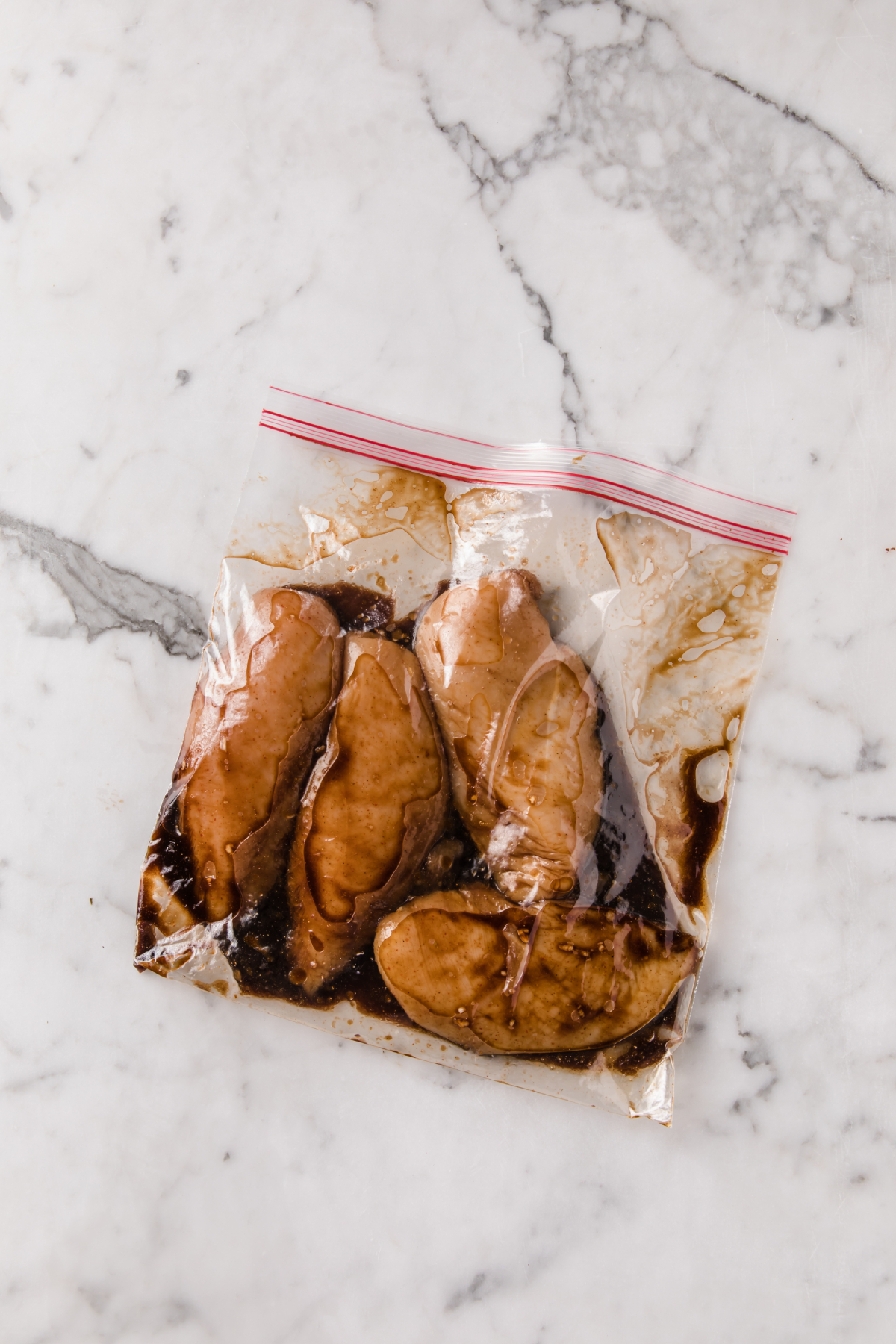 una bolsa zip con pechugas de pollo crudas marinadas