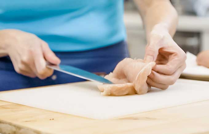 una persona mostrando una pechuga de pollo fileteada para rellenar