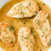 un plato con cuatro pechugas de pollo al vino blanco cocidas.