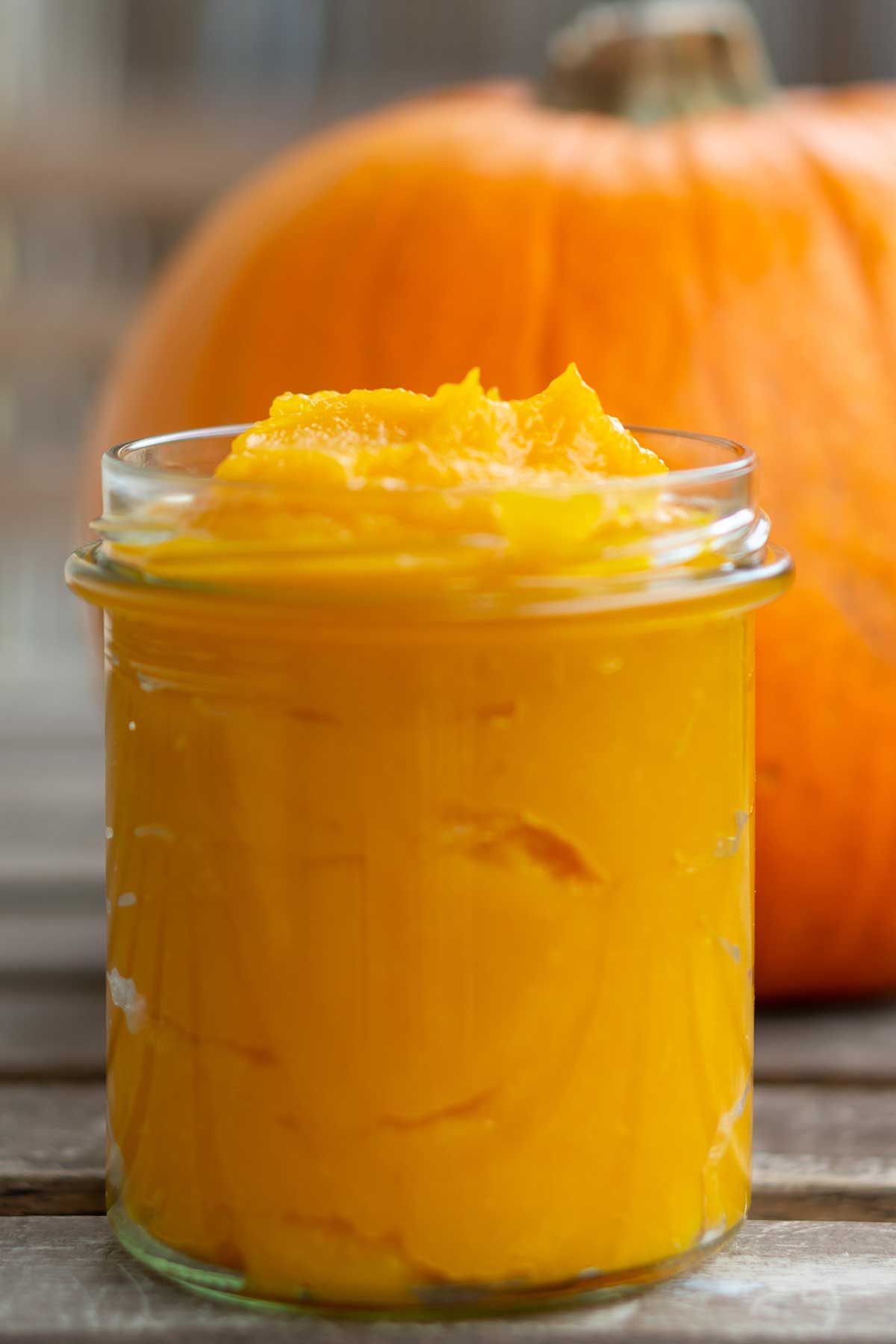 un frasco con puré de calabaza y detrás, una calabaza