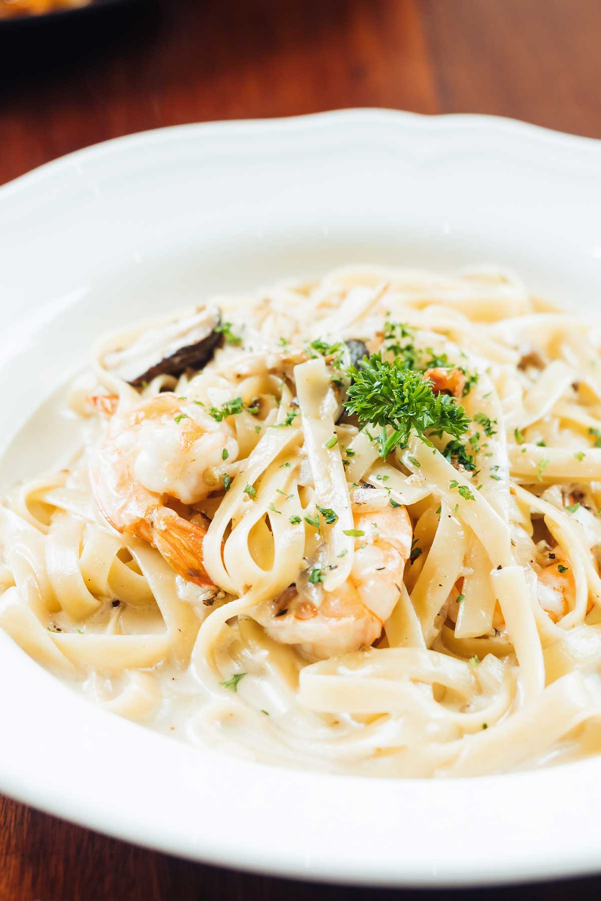 un plato de pasta con salsa alfredo y camarones
