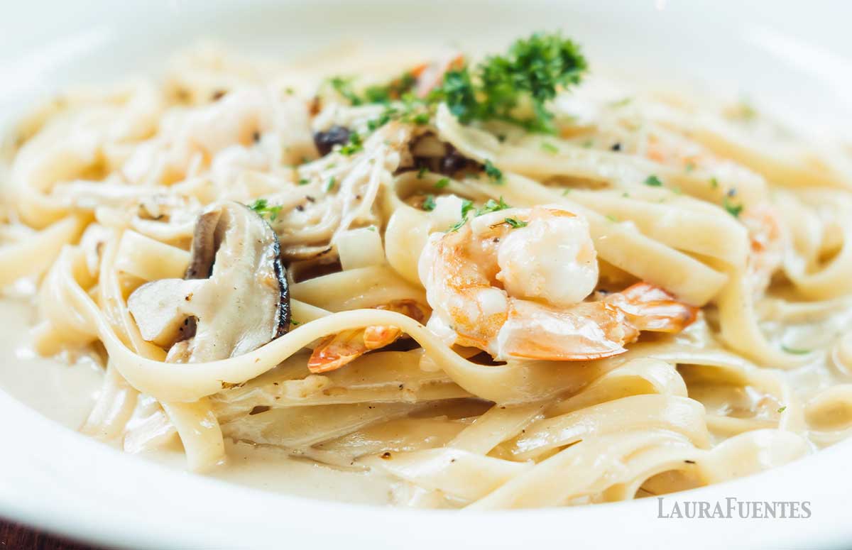 un plato de pasta con salsa alfredo y camarones