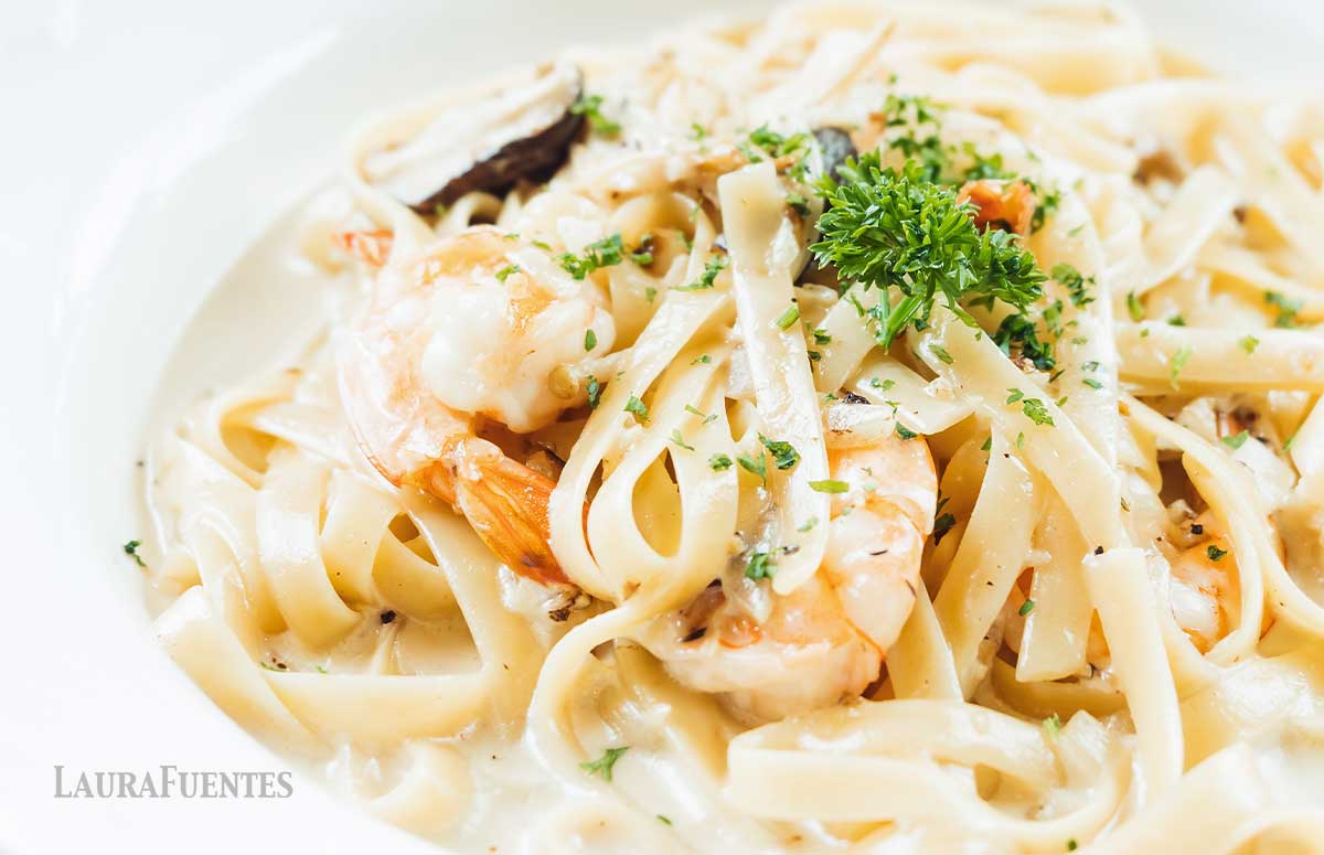 un plato de pasta con salsa alfredo y camarones