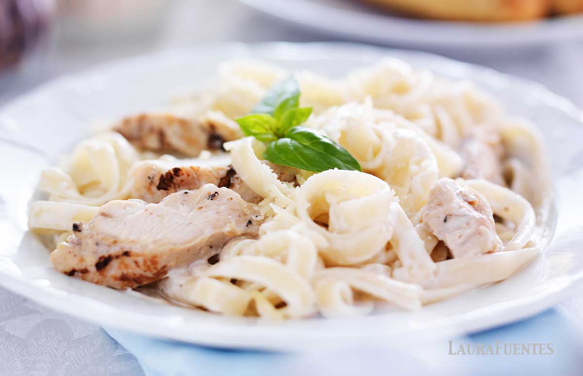 un plato de pasta con salsa alfredo y pollo