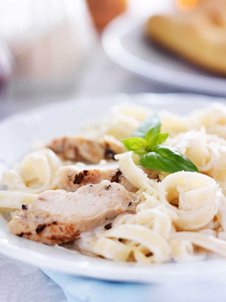 un plato de pasta con salsa alfredo y pollo