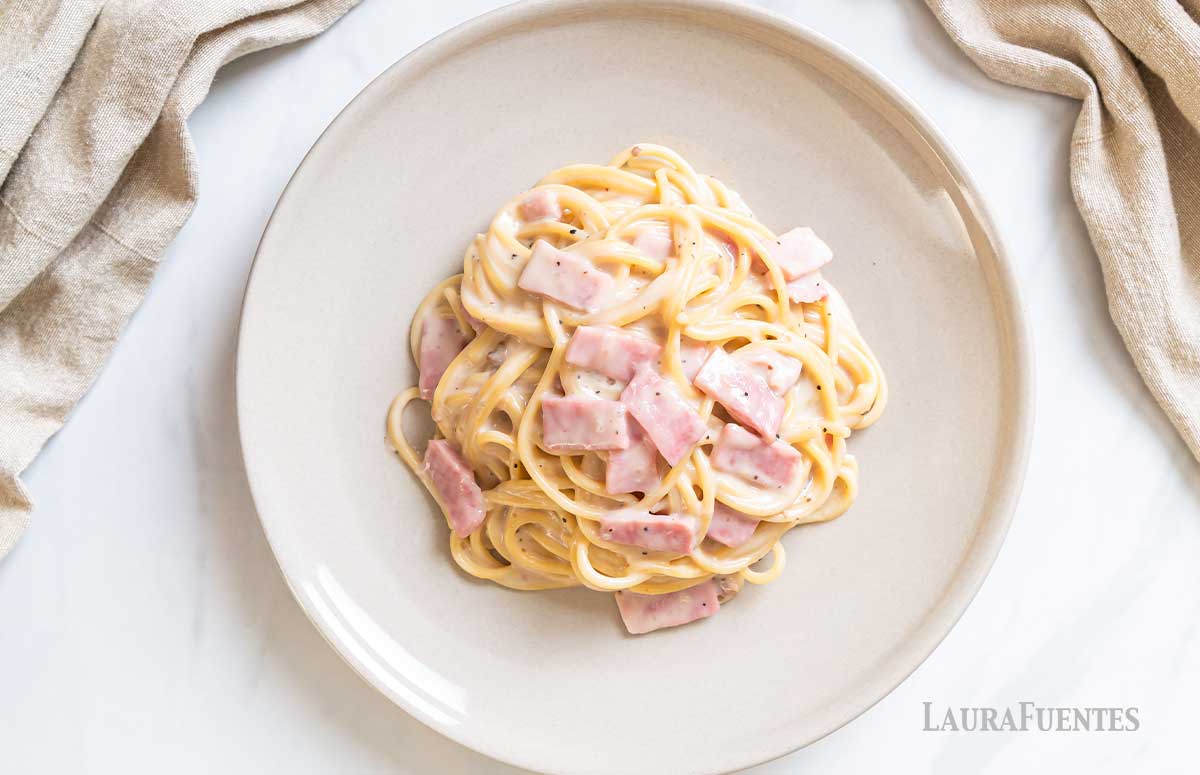 un plato de espaguetis alfredo con jamón york