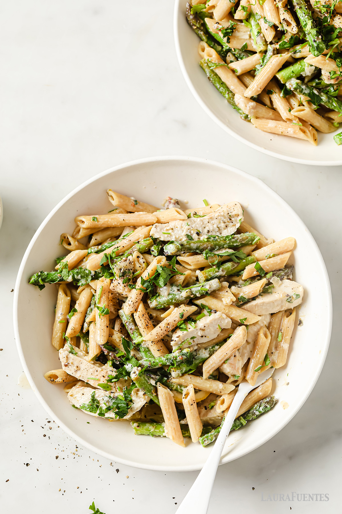 dos platos de pasta con espárragos y pollo