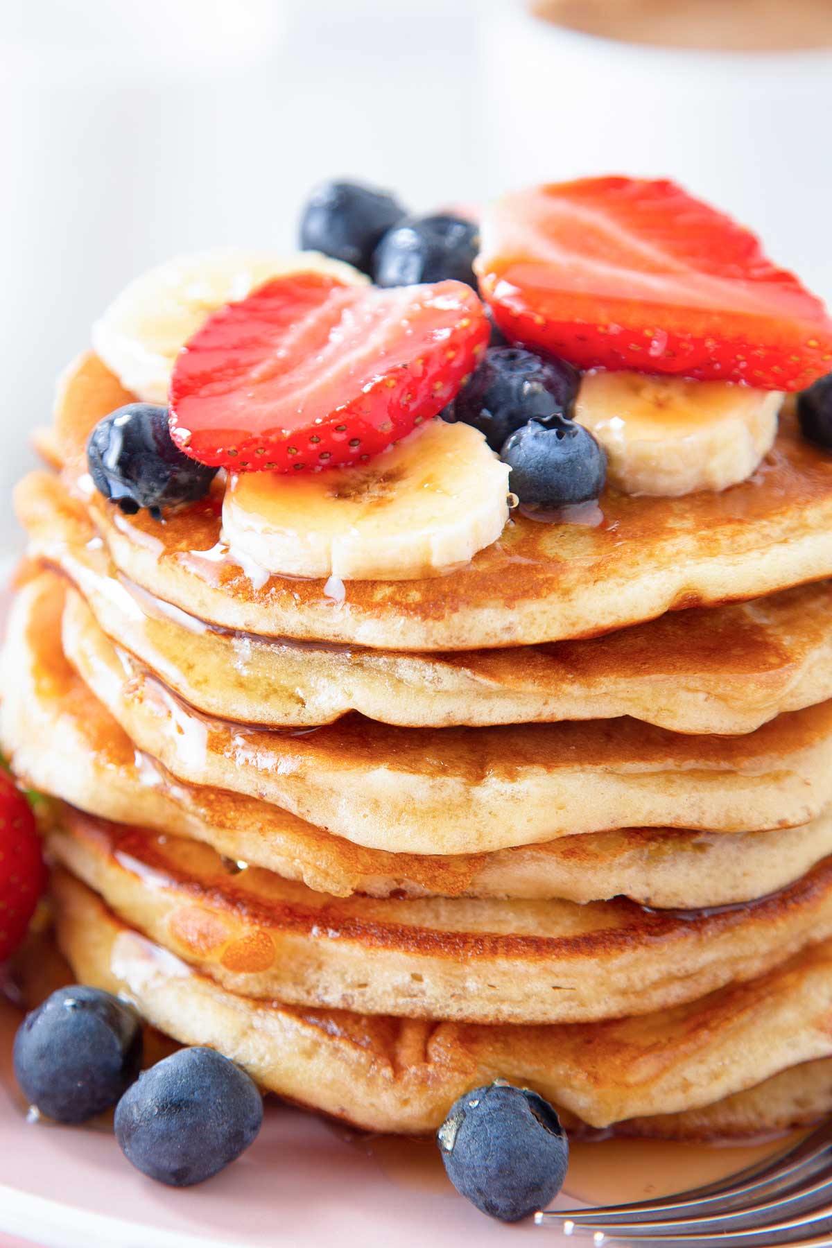 una pila de tortitas con plátano, fresas y arándanos encima