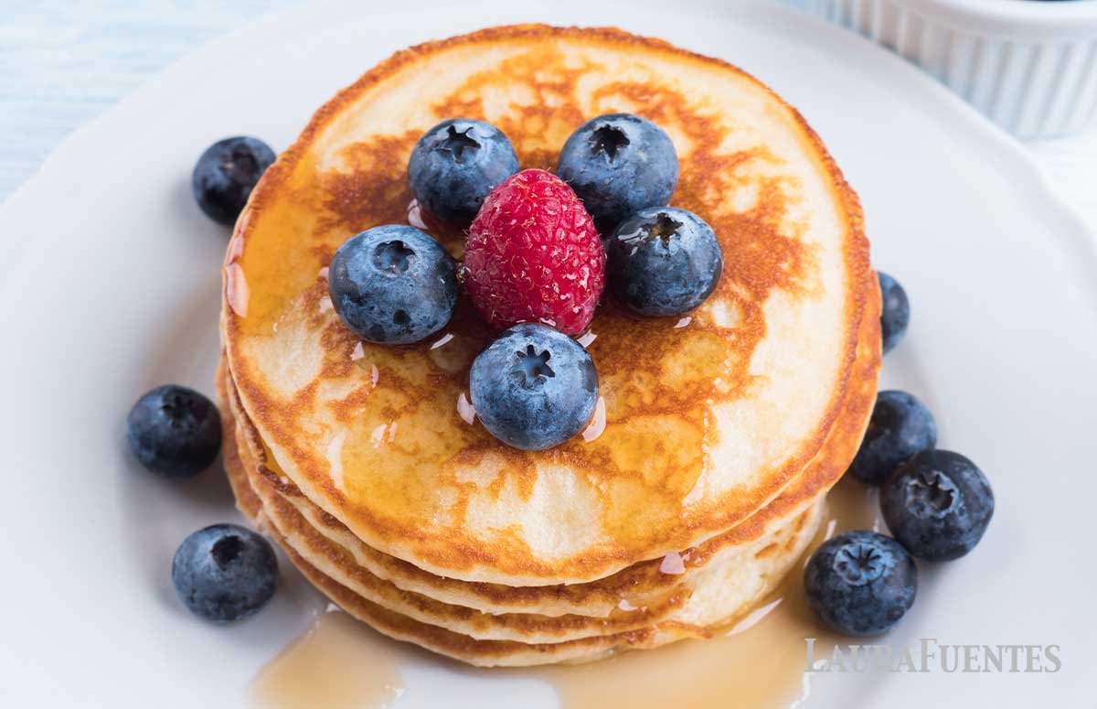 una pila de tortitas de yogur con miel y frutos rojos vista desde arriba