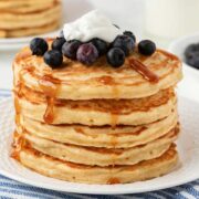 una pila de tortitas con arándanos y crema por encima