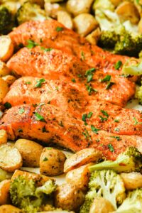 filetes de salmón rodeados de patatas horneados y algunos trozos de brócoli