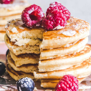 una pila de tortitas con moras por encima
