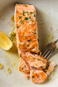 un filete de salmón en un plato y un tenedor pinchando un trozo