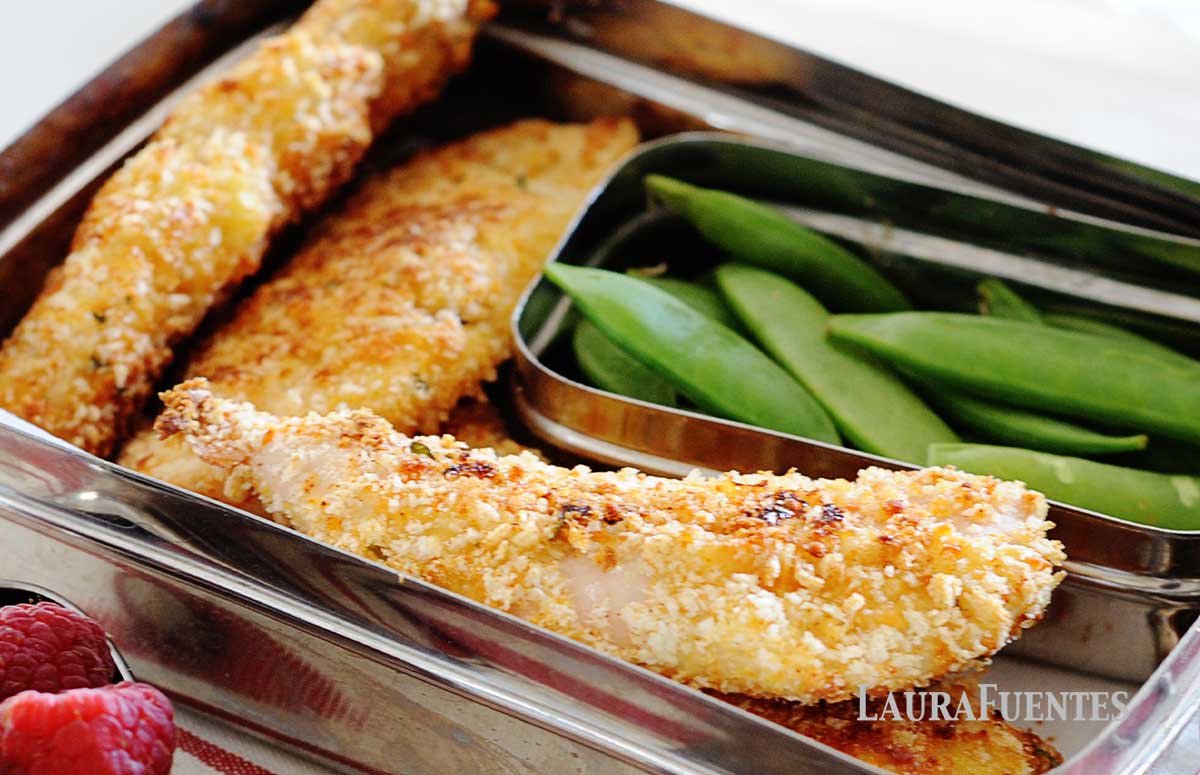 una lonchera con tres tiras de pollo rebozado y unas cuantas judías verdes