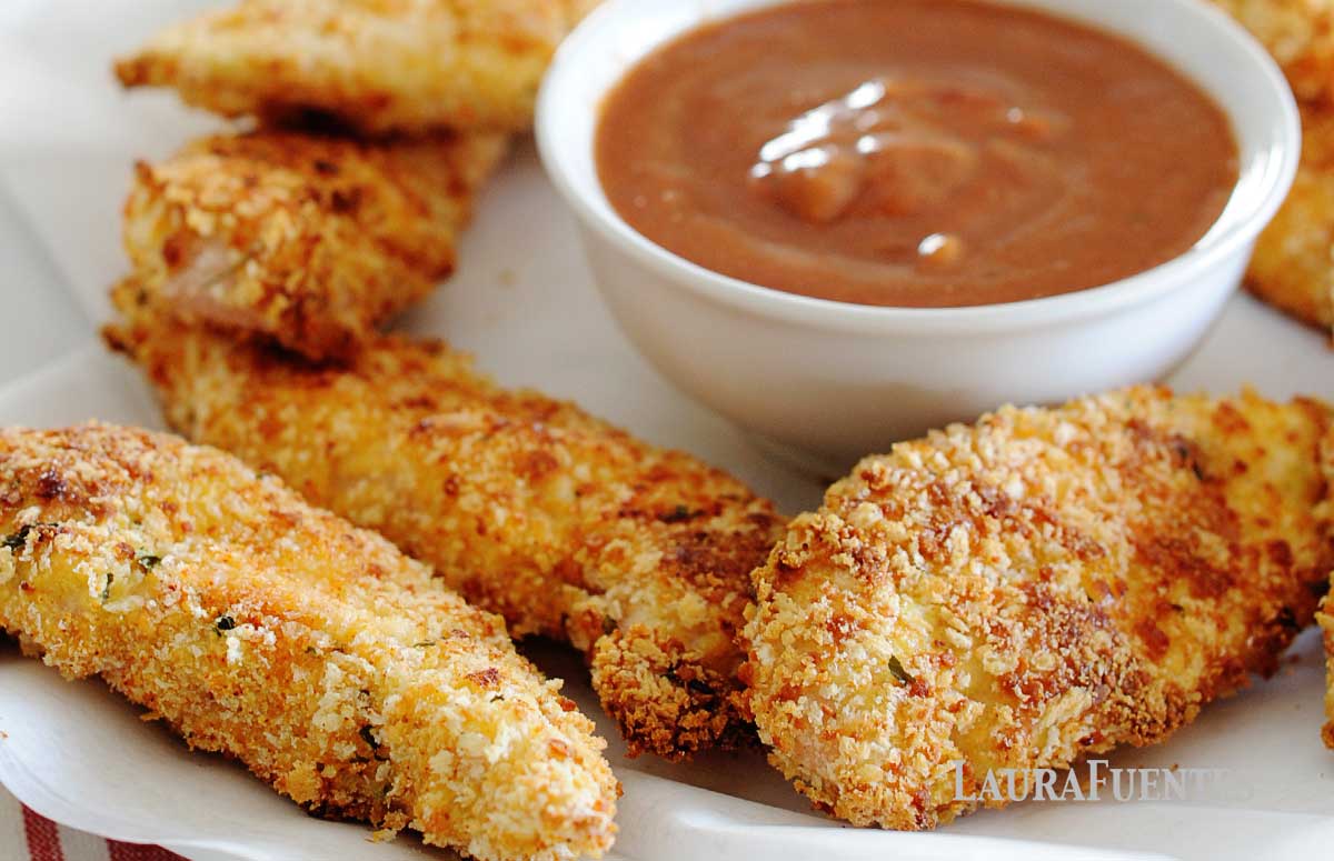 tiras de pollo rebozado junto a un pequeño bol con aderezo