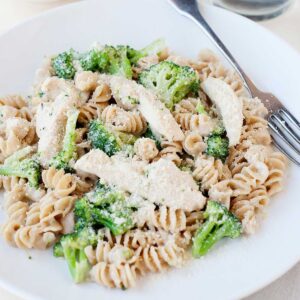 un plato de pasta alfredo con pollo y brócoli
